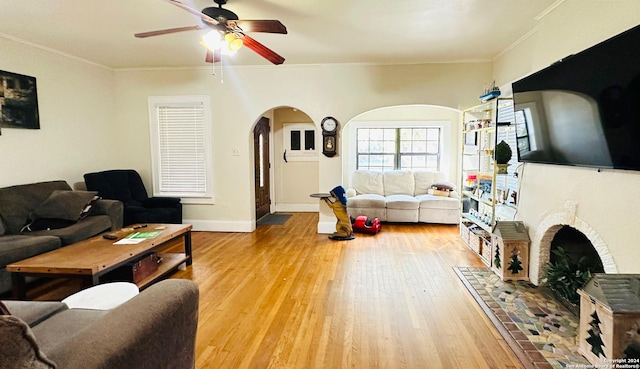 living room featuring hardwood / wood-style flooring, ceiling fan, crown molding, and a tile fireplace