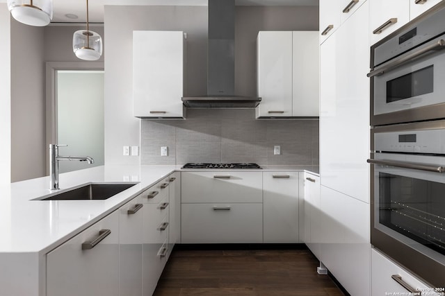 kitchen featuring white cabinetry, sink, wall chimney exhaust hood, dark hardwood / wood-style floors, and pendant lighting