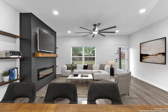 living room with ceiling fan, a fireplace, and wood-type flooring