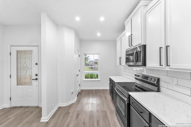 kitchen featuring light stone countertops, appliances with stainless steel finishes, light hardwood / wood-style flooring, and white cabinetry