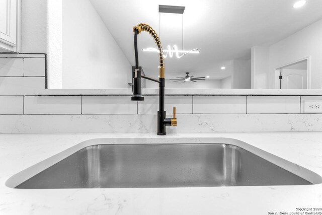 details with white cabinetry, sink, ceiling fan, light stone countertops, and decorative light fixtures