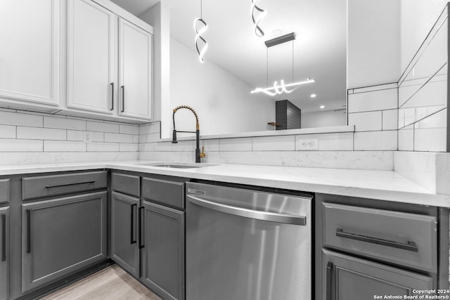 kitchen featuring dishwasher, backsplash, sink, gray cabinets, and light stone countertops