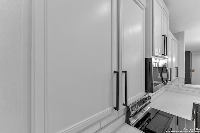 room details featuring light stone countertops, white cabinetry, and stainless steel appliances