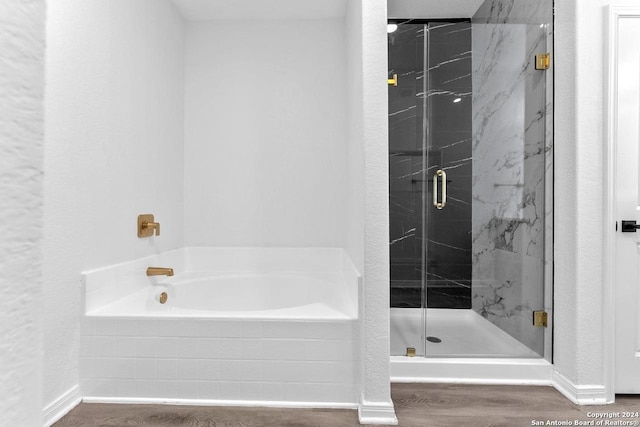 bathroom with wood-type flooring and shower with separate bathtub