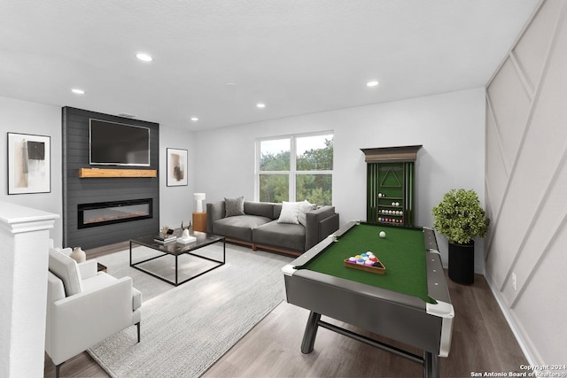 playroom with wood-type flooring, a large fireplace, and pool table