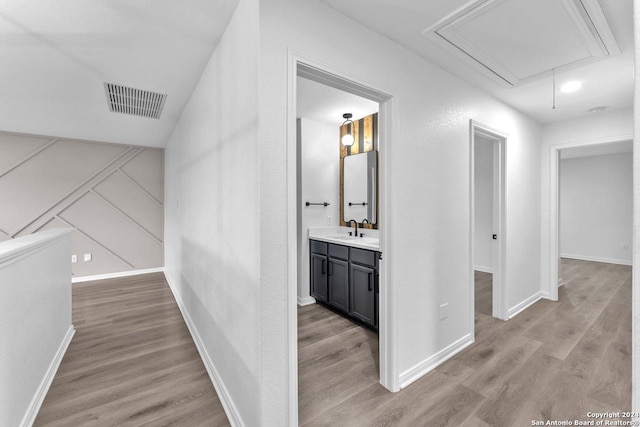 hallway with sink and light hardwood / wood-style flooring