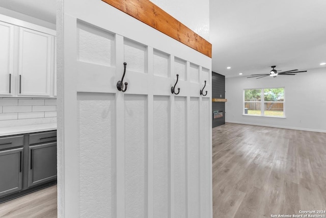 mudroom with ceiling fan, a fireplace, and light hardwood / wood-style flooring