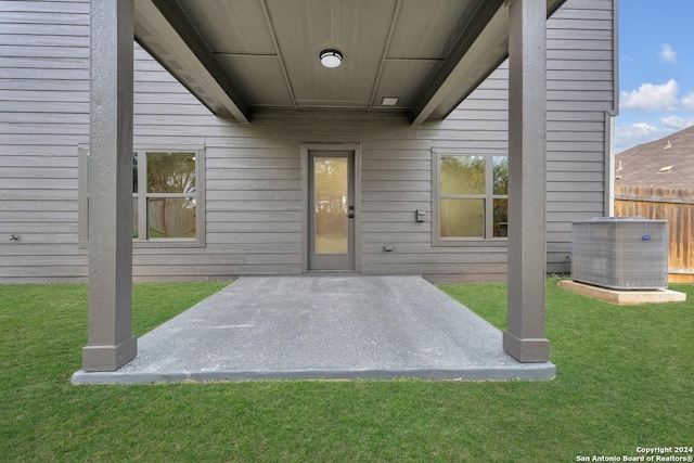 doorway to property with a yard, central AC unit, and a patio area