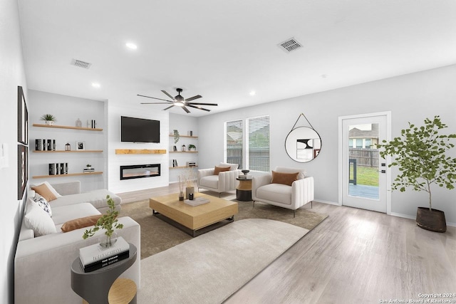 living room featuring a wealth of natural light, a fireplace, ceiling fan, and wood-type flooring