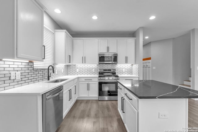 kitchen featuring a center island, white cabinets, sink, light hardwood / wood-style floors, and stainless steel appliances