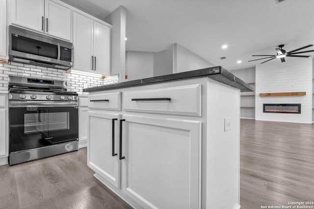 kitchen featuring white cabinets, ceiling fan, appliances with stainless steel finishes, a large fireplace, and light hardwood / wood-style floors