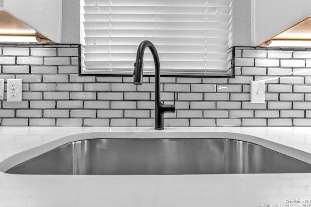 room details featuring decorative backsplash, sink, and light stone counters