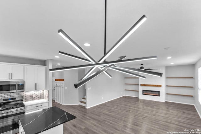 kitchen with ceiling fan, a fireplace, appliances with stainless steel finishes, dark hardwood / wood-style flooring, and white cabinetry