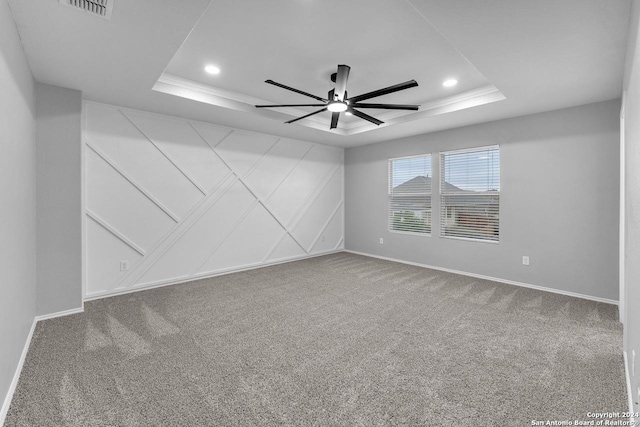 carpeted spare room with a tray ceiling and ceiling fan