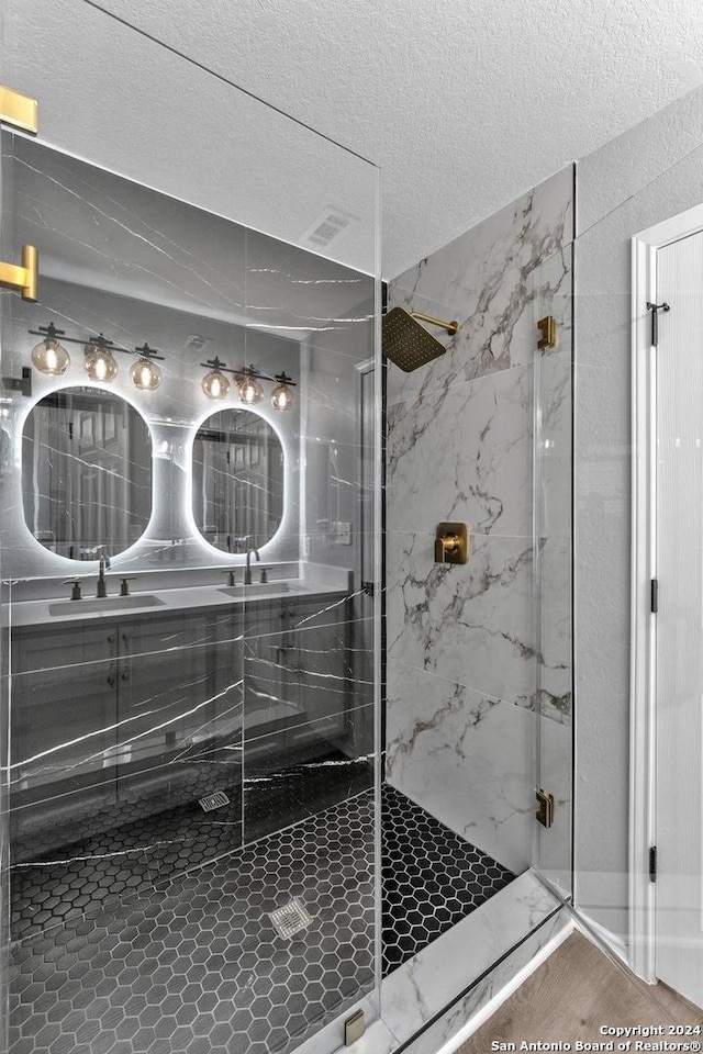 bathroom with sink, an enclosed shower, a textured ceiling, and wood-type flooring