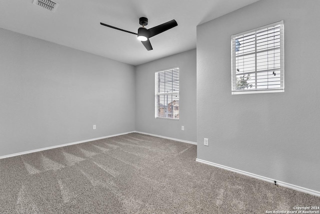 spare room with carpet floors, a wealth of natural light, and ceiling fan