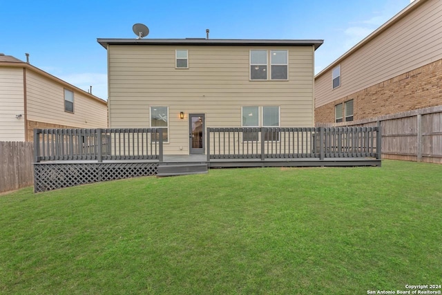 rear view of property with a yard and a wooden deck