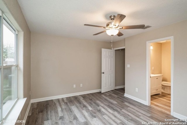 unfurnished bedroom with connected bathroom, ceiling fan, light hardwood / wood-style floors, and a textured ceiling