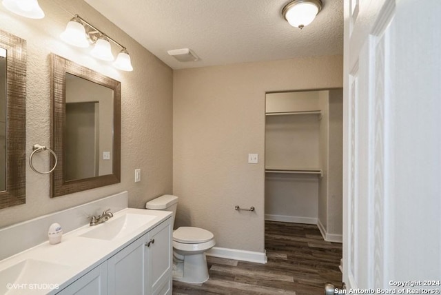 bathroom featuring hardwood / wood-style flooring, vanity, toilet, and a textured ceiling