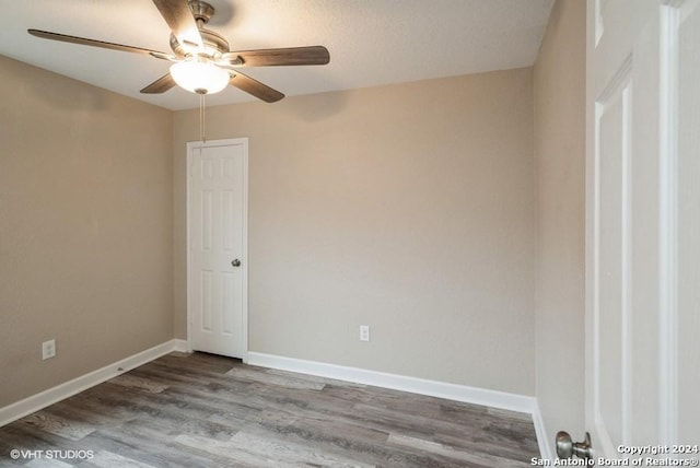 empty room with ceiling fan, wood-type flooring, and a textured ceiling