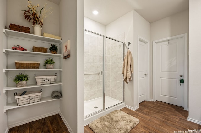 bathroom with hardwood / wood-style flooring and a shower with shower door