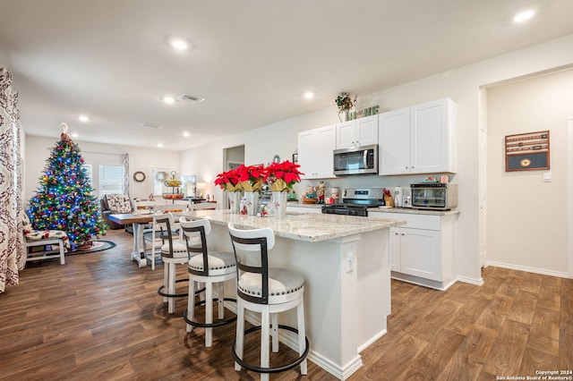 kitchen featuring a kitchen island with sink, white cabinets, hardwood / wood-style flooring, and appliances with stainless steel finishes