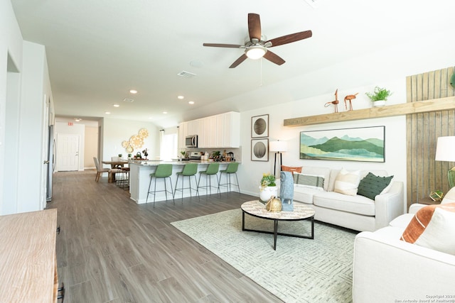 living room featuring ceiling fan and dark wood-type flooring