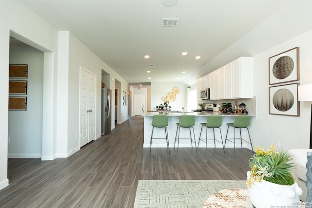 kitchen featuring white cabinetry, a kitchen breakfast bar, dark hardwood / wood-style floors, stainless steel appliances, and kitchen peninsula