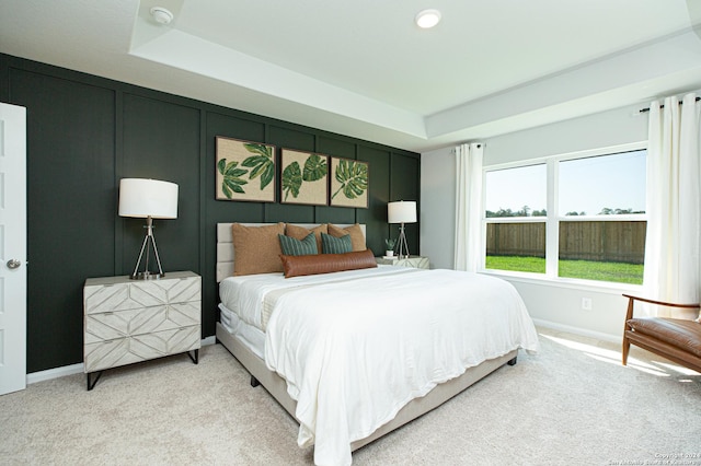 bedroom with carpet floors and a raised ceiling