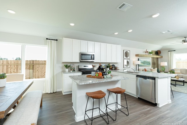 kitchen with kitchen peninsula, a breakfast bar, a kitchen island, appliances with stainless steel finishes, and white cabinets