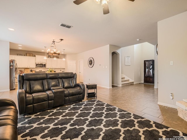 tiled living room featuring ceiling fan with notable chandelier