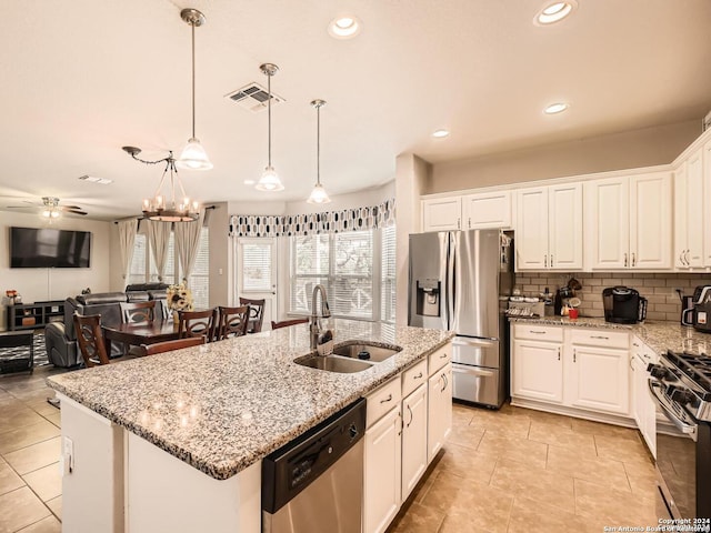 kitchen with sink, an island with sink, decorative light fixtures, white cabinets, and appliances with stainless steel finishes