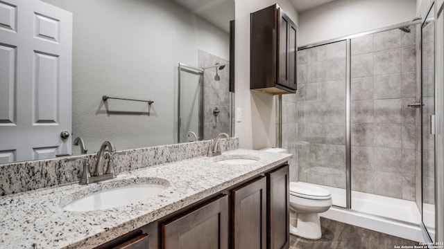 bathroom with hardwood / wood-style flooring, vanity, toilet, and an enclosed shower