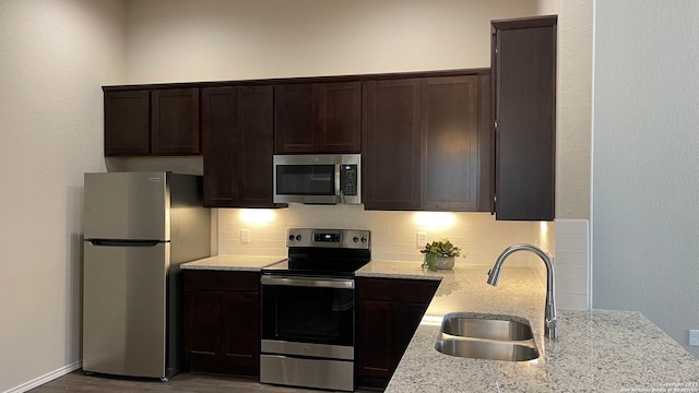 kitchen featuring decorative backsplash, sink, light stone counters, and stainless steel appliances