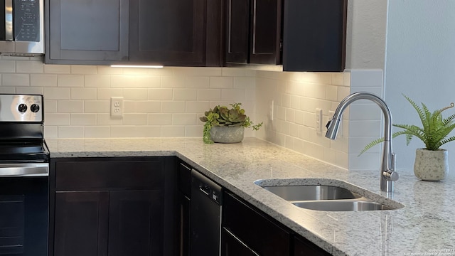 kitchen with light stone countertops, decorative backsplash, sink, and stainless steel appliances