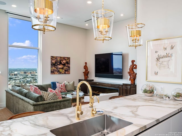 kitchen with decorative light fixtures, light stone counters, and sink