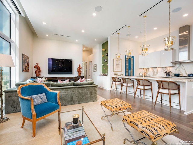 living room featuring light hardwood / wood-style floors, a towering ceiling, and an inviting chandelier