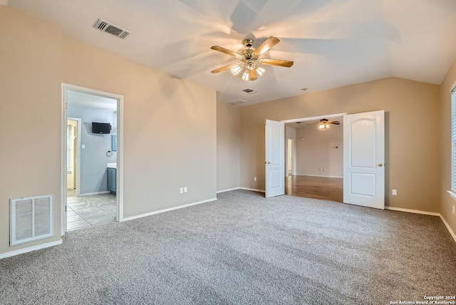 unfurnished bedroom featuring ceiling fan, vaulted ceiling, light carpet, and ensuite bath