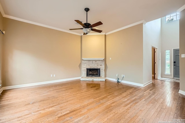 unfurnished living room with crown molding, a fireplace, ceiling fan, and light wood-type flooring