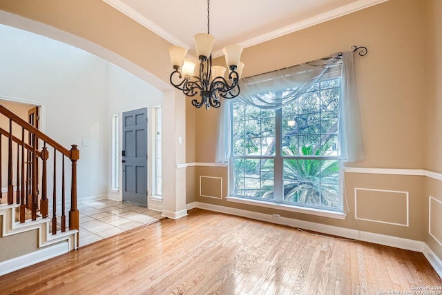 interior space with crown molding, light hardwood / wood-style flooring, and an inviting chandelier