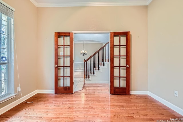 unfurnished room featuring french doors, light wood-type flooring, and ornamental molding