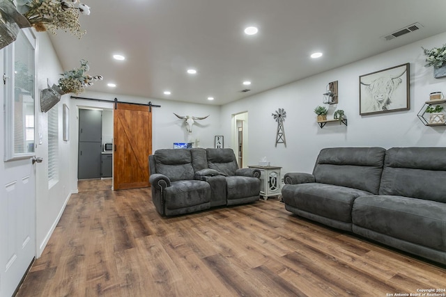 living room with a barn door and dark wood-type flooring