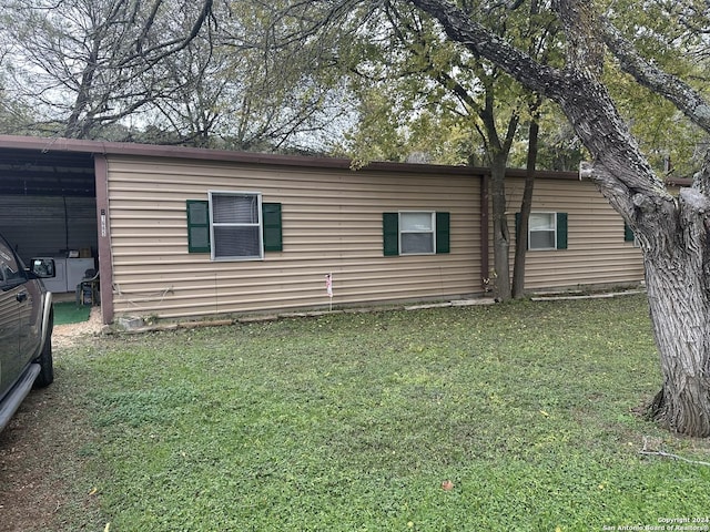 view of home's exterior with a carport and a yard