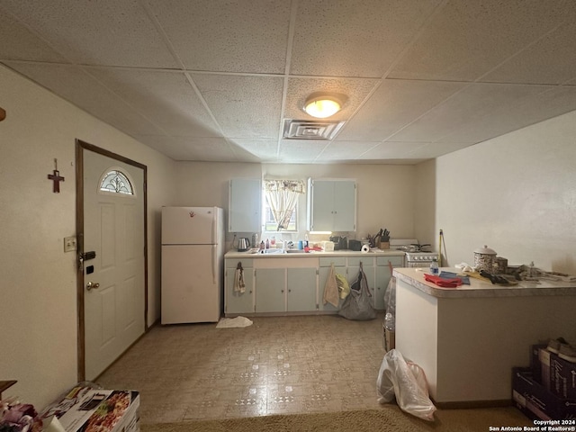 kitchen featuring a paneled ceiling, sink, stainless steel stove, and white refrigerator