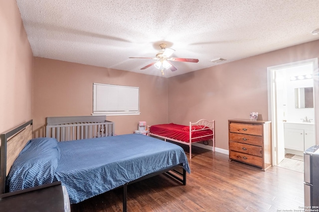 bedroom featuring sink, ensuite bath, ceiling fan, a textured ceiling, and wood-type flooring