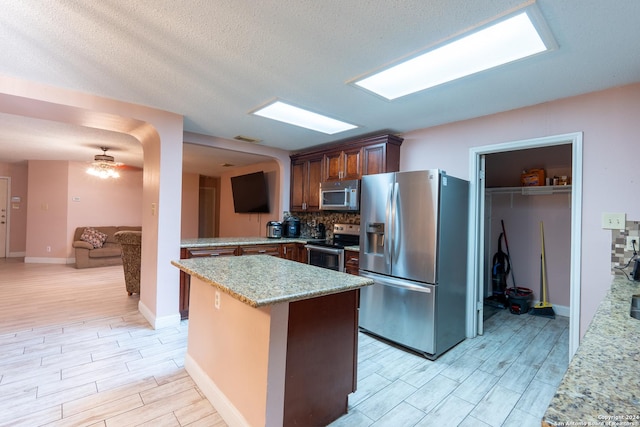 kitchen with ceiling fan, light wood-type flooring, a textured ceiling, and appliances with stainless steel finishes