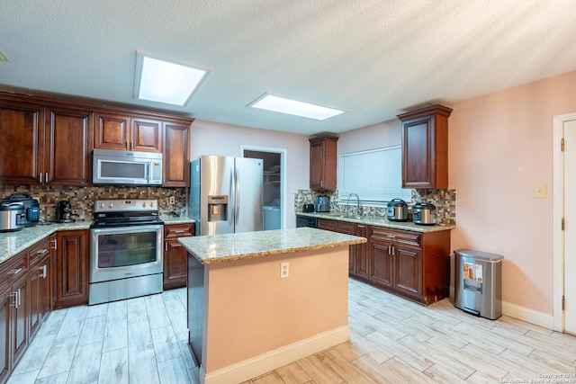 kitchen with light wood-type flooring, appliances with stainless steel finishes, a center island, and backsplash