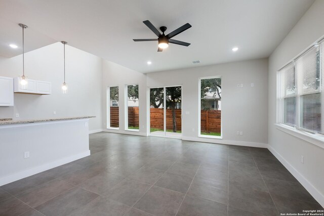 unfurnished living room featuring dark tile patterned flooring, plenty of natural light, and ceiling fan