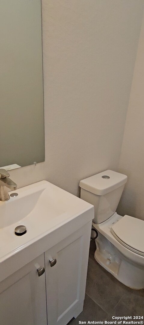 bathroom with toilet, vanity, and tile patterned floors