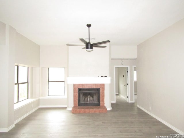 unfurnished living room with ceiling fan, a fireplace, and wood-type flooring